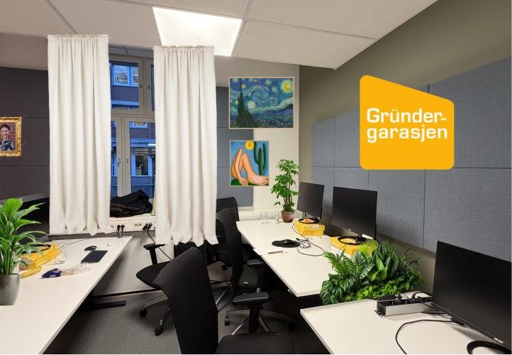 A work room with light curtains, plants, framed art and a Gr&uuml;ndergarasjen logo on the wall, above rows of desks.